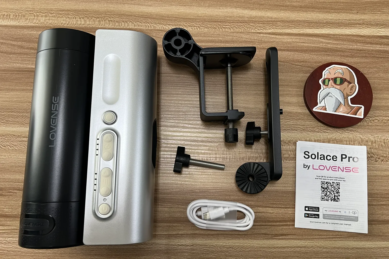 Lovense Solace Proの開封内容。本体、デスク固定用クランプ、USB-C充電ケーブル、説明書が並んでいる