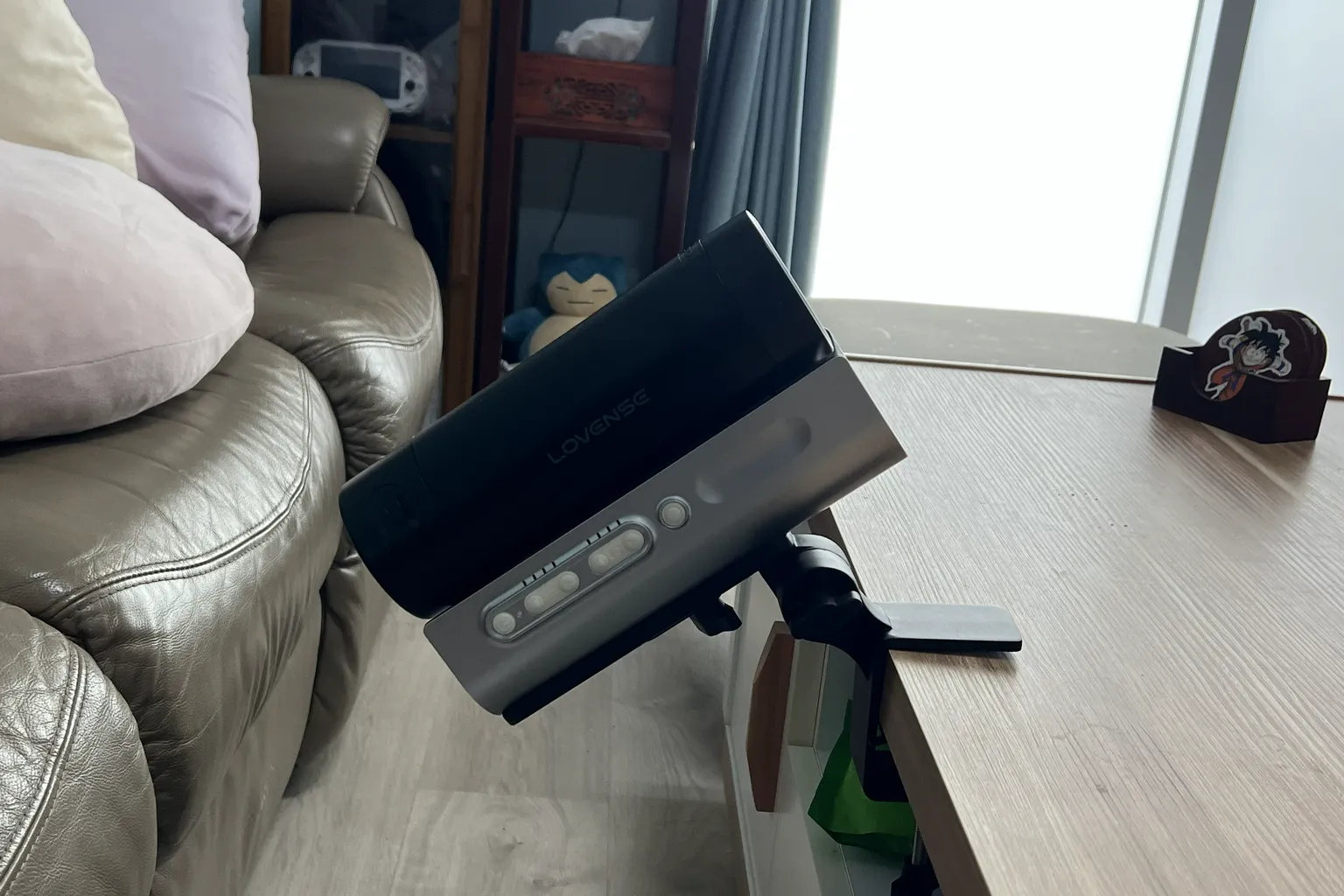 Lovense Solace Proを付属のデスク固定クランプでテーブルの端に取り付けた様子。本体を斜めに傾けている